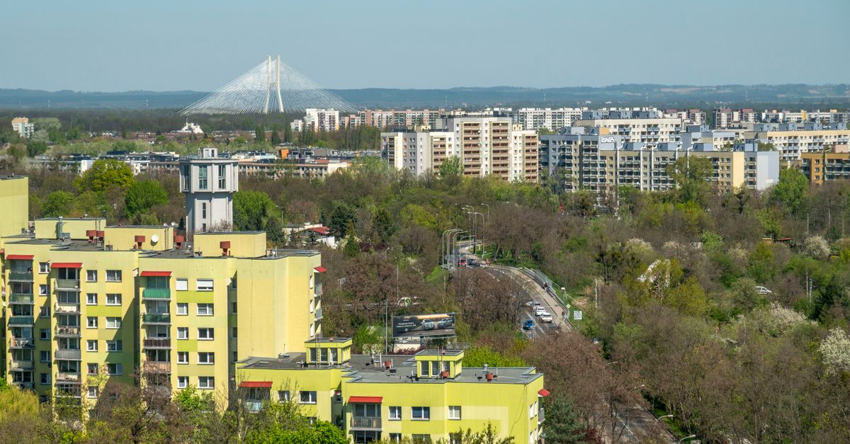 Aerial view of Wrocław cityscape highlighting residential buildings and a distinct bridge in the distance.