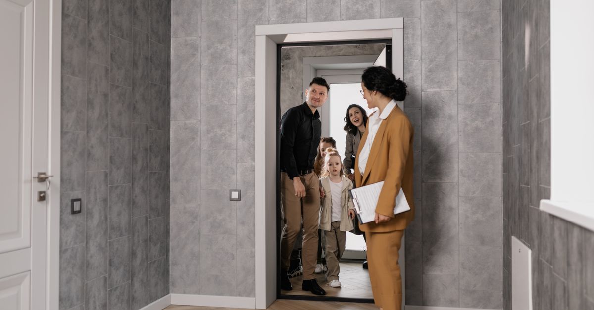 A family explores a new home with a real estate agent in a modern interior setting.